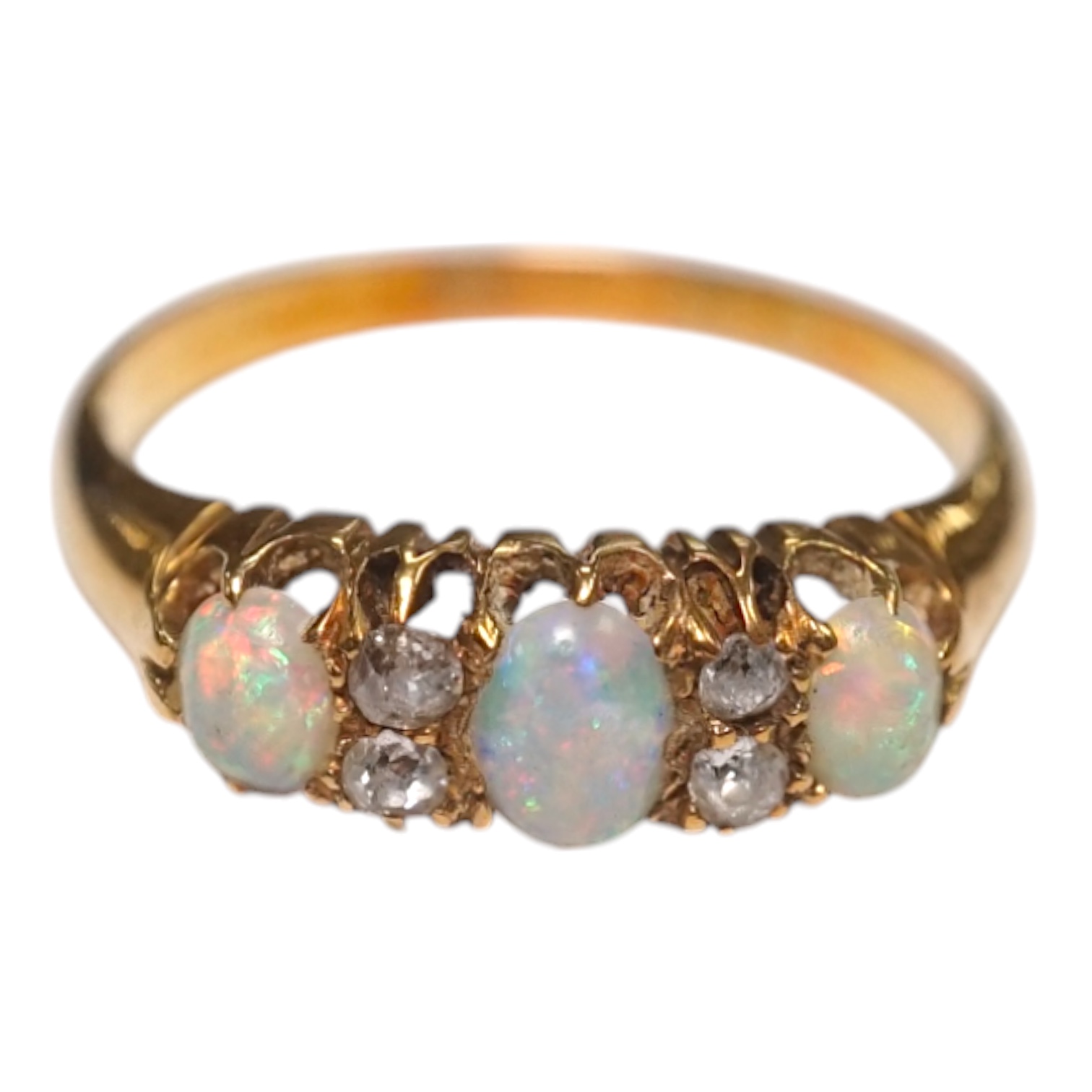 An early 20th century yellow metal and three stone white opal ring, with four stone diamond chip spacers, size M/N, gross weight 3 grams. Condition - poor to fair